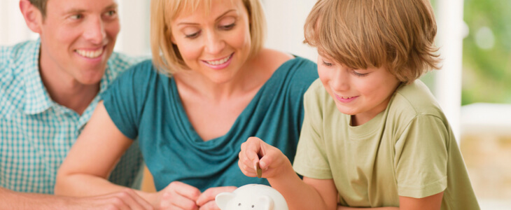 couple with young son putting coin in a piggy bank
