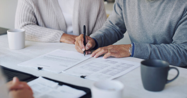 Older woman signing estate planning documents with attorney