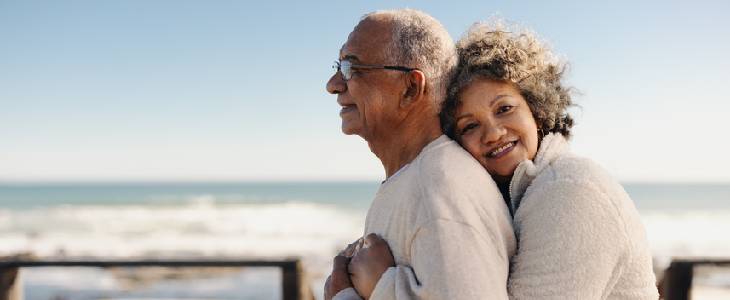 Elderly couple on the boardwalk of a beach hugging each other