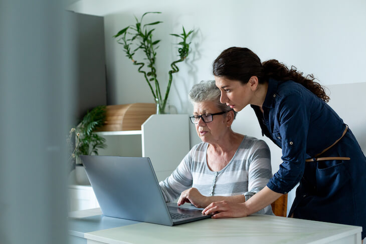 young woman helping senior relative with computer