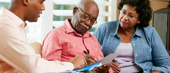 older couple signing papers with their son