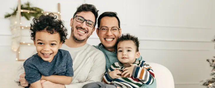 a same sex couple with two young children on their laps