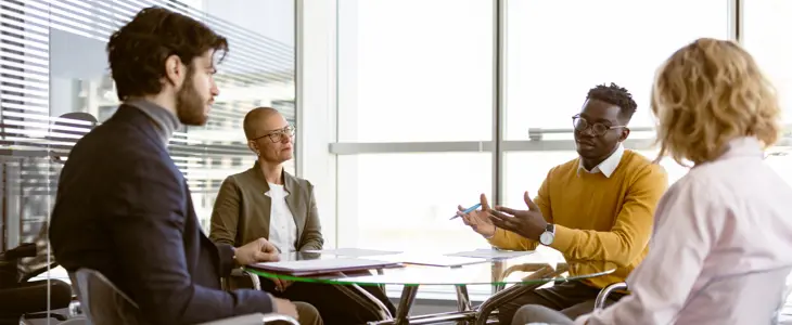 Four people sitting around a desk discussing business