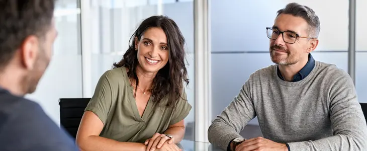 a young couple sitting at a desk with papers to sign