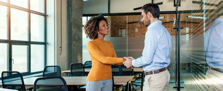 a woman and a man shaking hands in an office conference room