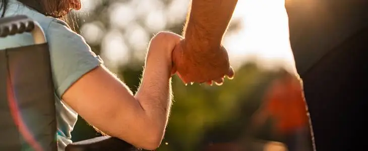 Young father holding on to the hand of his special needs daughter
