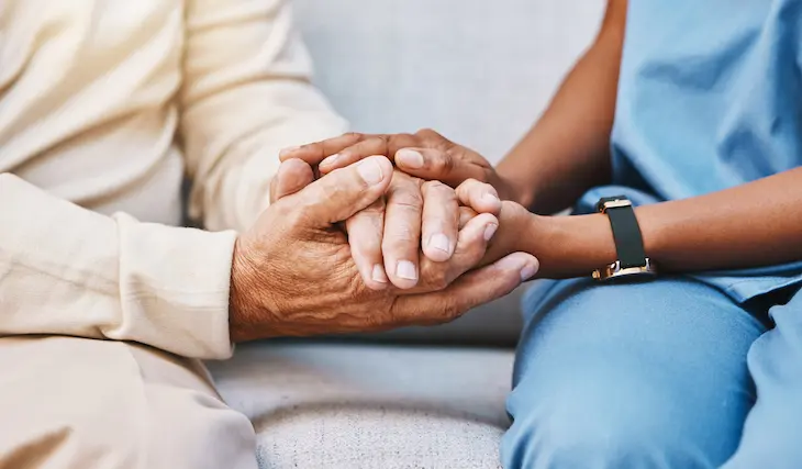 nurse hands holding the hands of s eenior, providing comfort