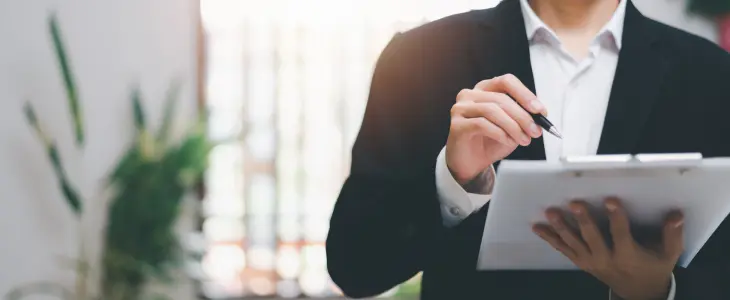 Businessman signing documents on a clipboard